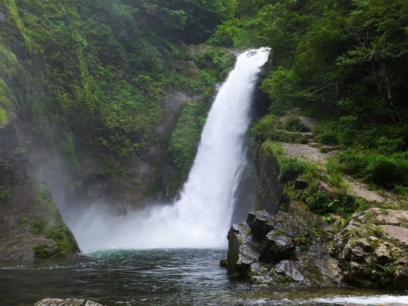 The Akiu Great Falls pouring into a green pool, surrounded by forest