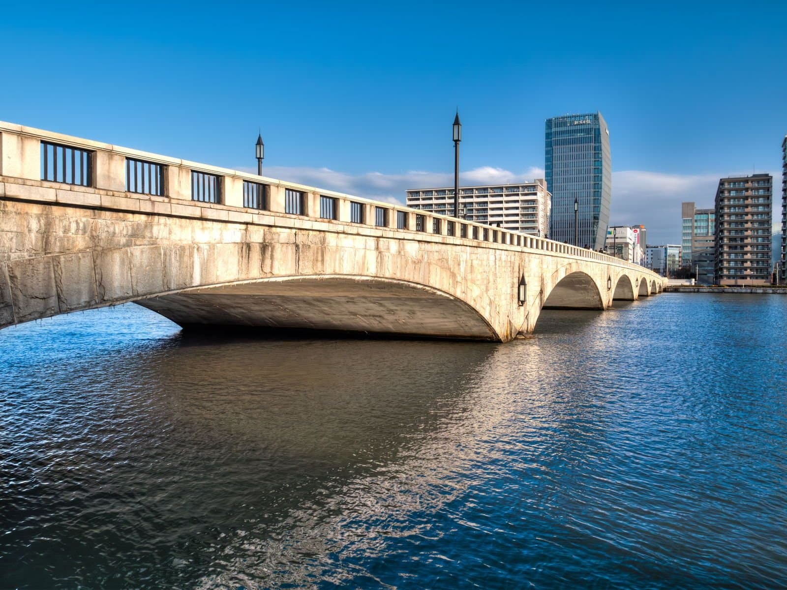 橫跨寬闊信濃川的萬代橋石造拱橋，後方是市區大樓