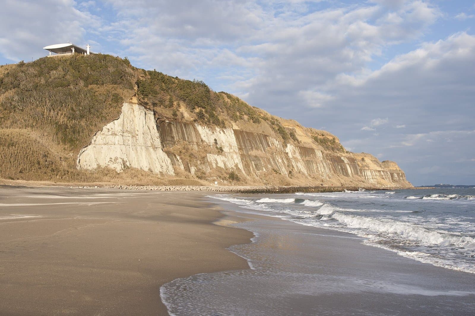 White layered cliffs above a sandy beach with waves