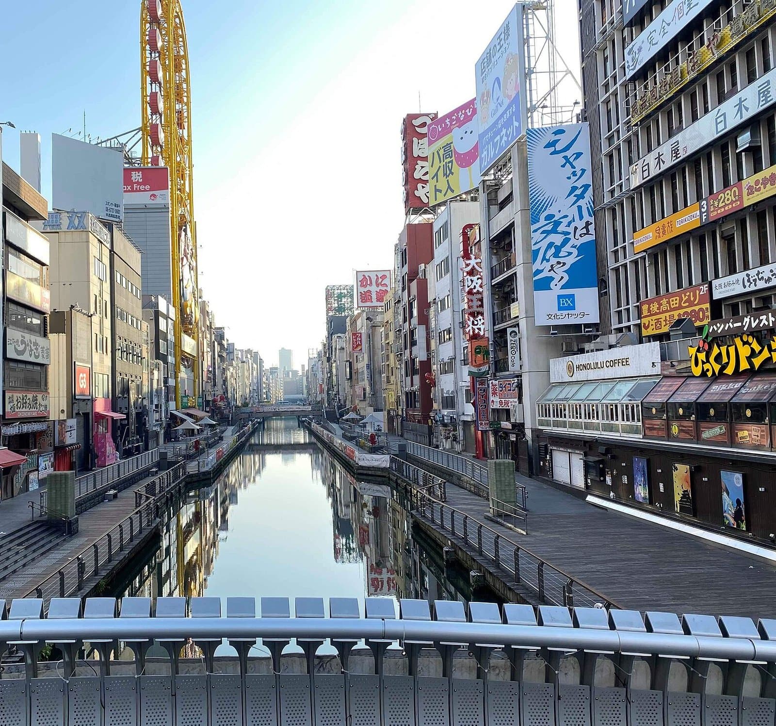 The Dotonbori canal lined with signboards and riverside walkways, seen from a bridge in the early morning