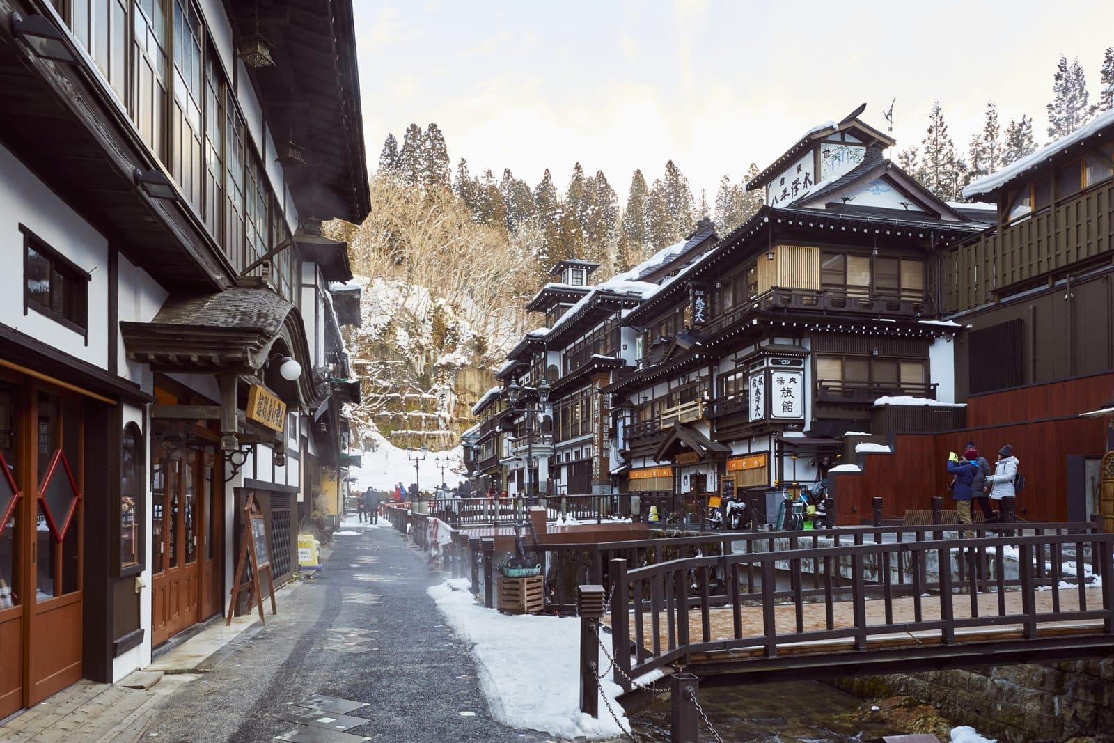 Snowy Ginzan Onsen, with multi-storey wooden inns and a wooden bridge along the river