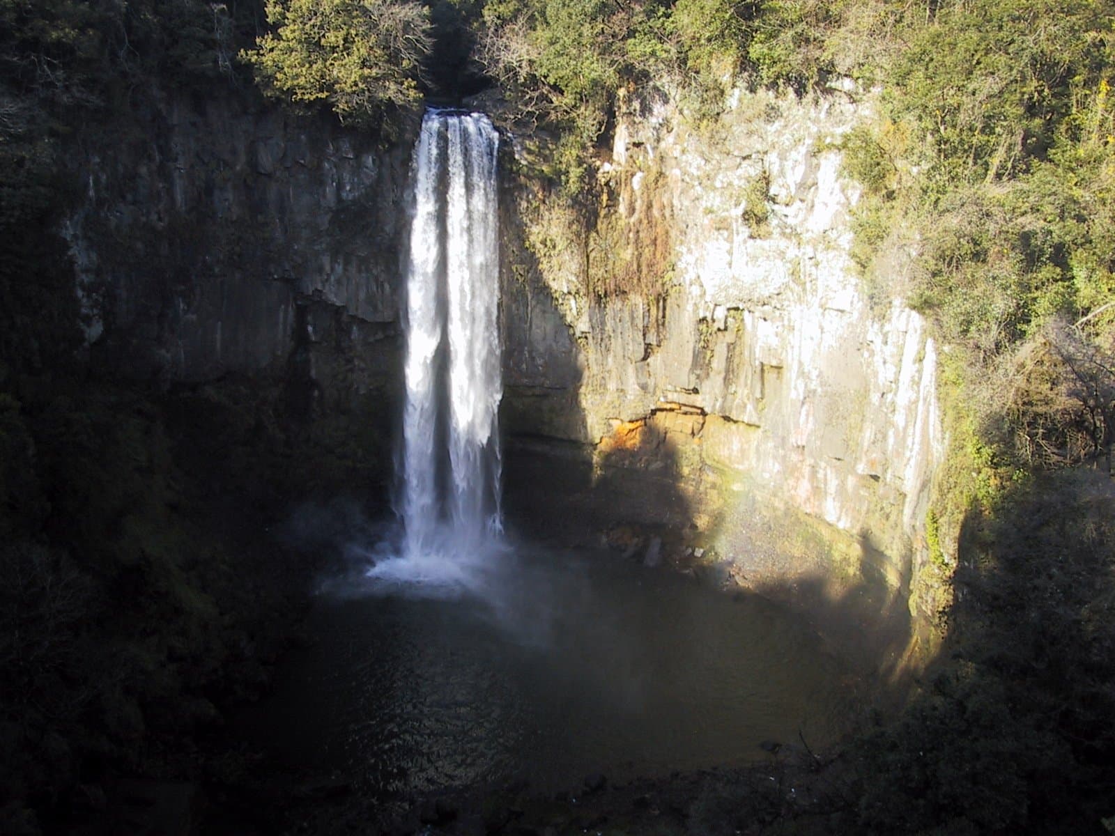 A tall, thin waterfall dropping down a dark cliff face