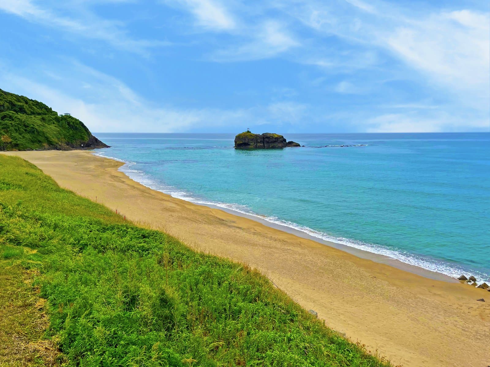 A curving sandy beach with a small island offshore