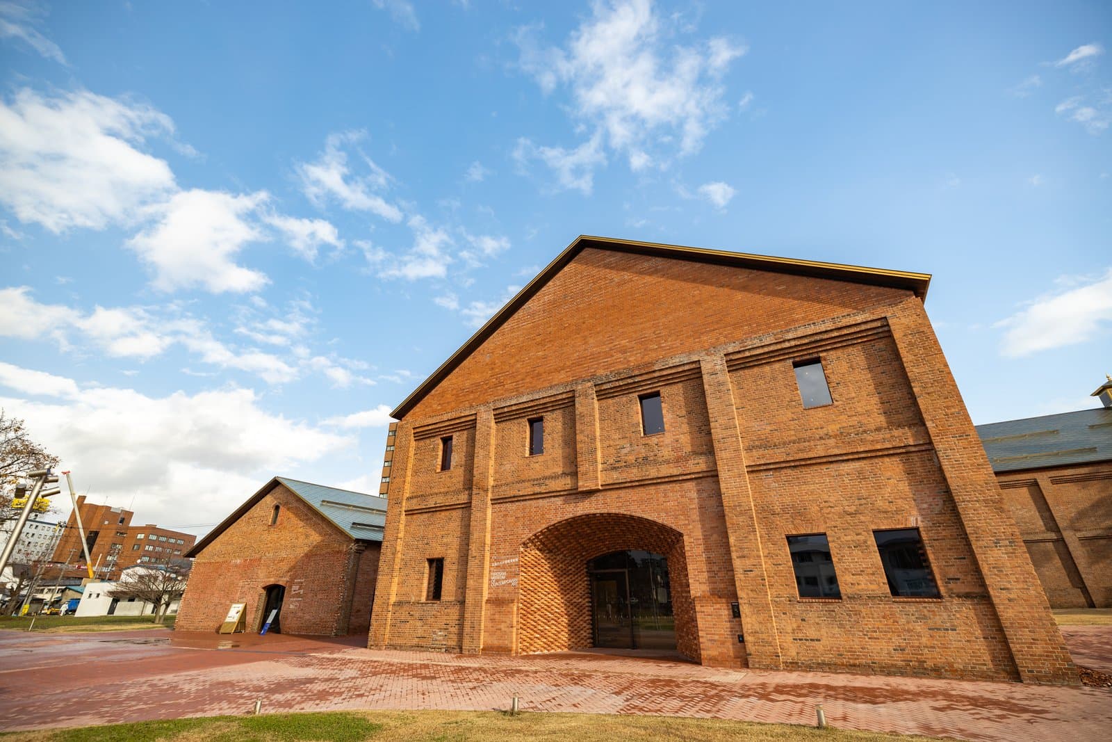 A tall brick warehouse with an arched entrance under a blue sky