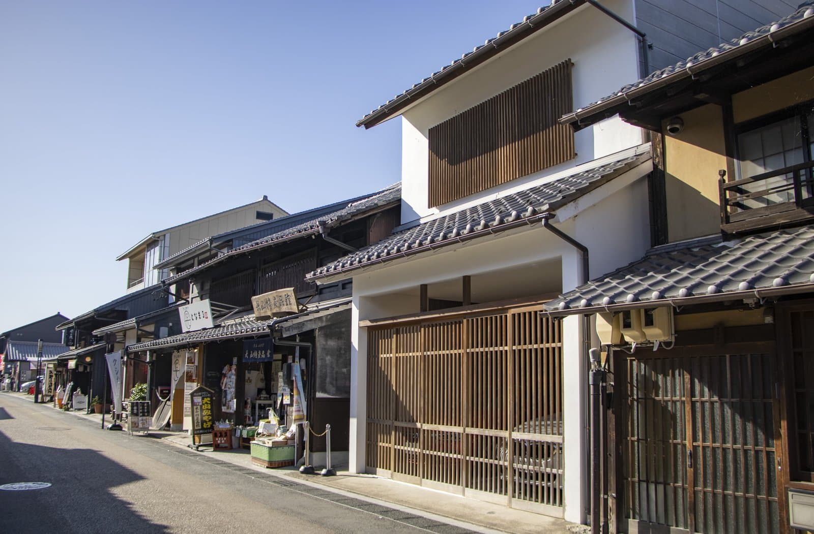 A street of traditional two-storey wooden townhouses and small shops under a clear sky