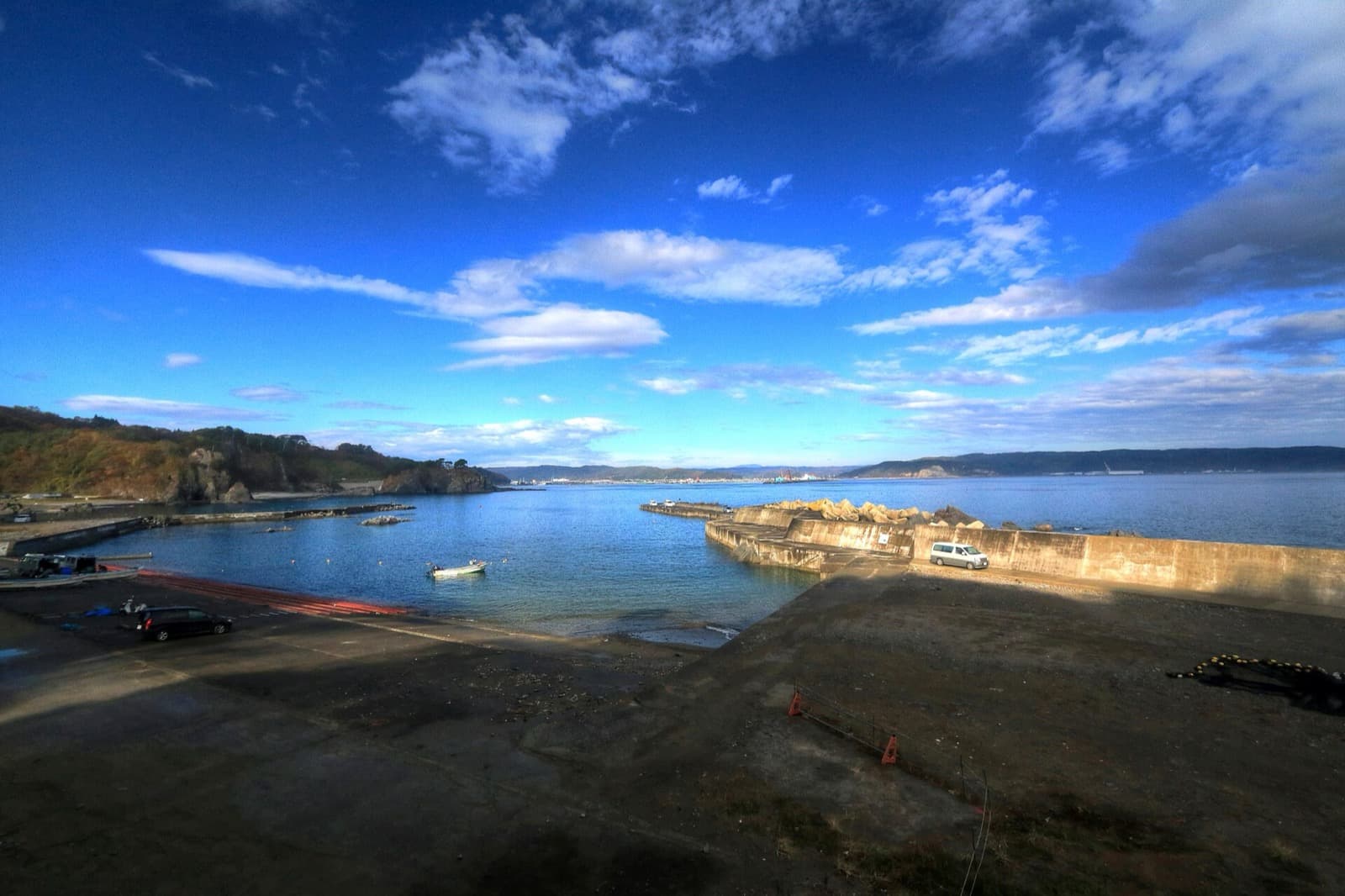 A small fishing harbour and cove on a rocky coast under a deep blue sky