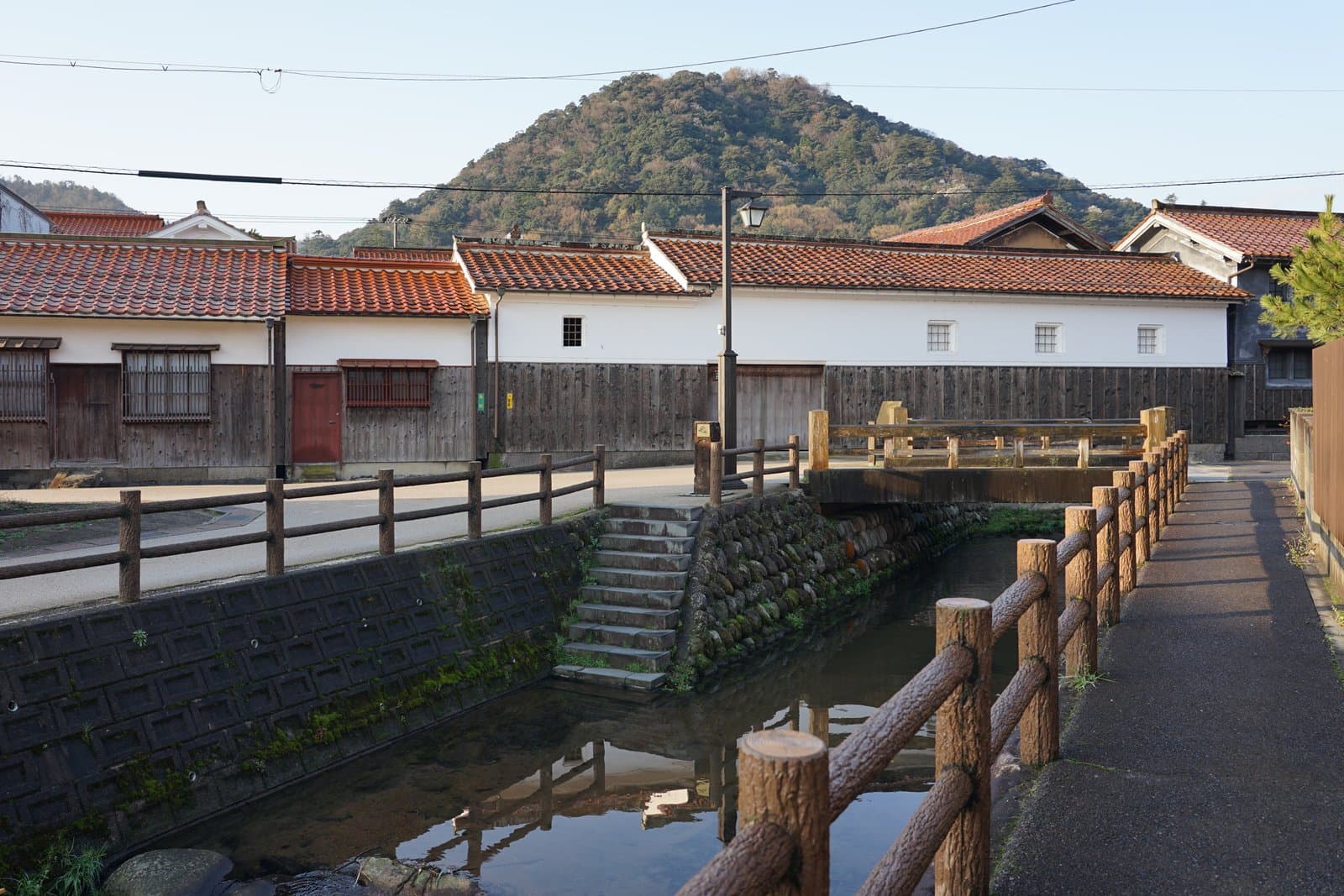 White-walled storehouses with red tiled roofs along a narrow canal