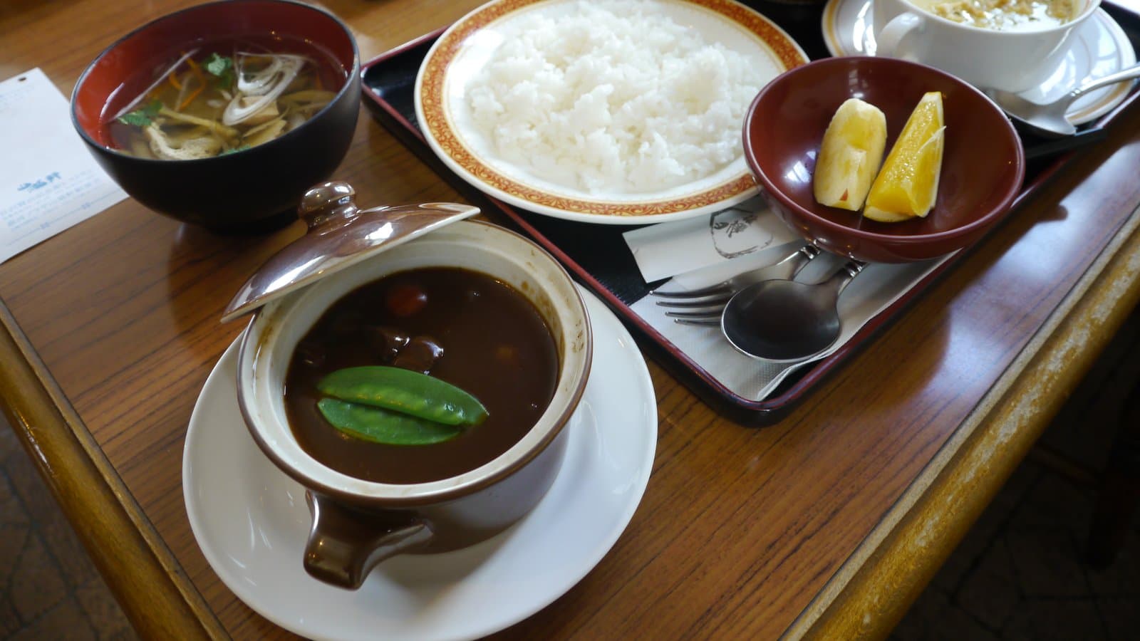 ふた付きの器のシチュー、ご飯、汁物、サラダ、果物の定食