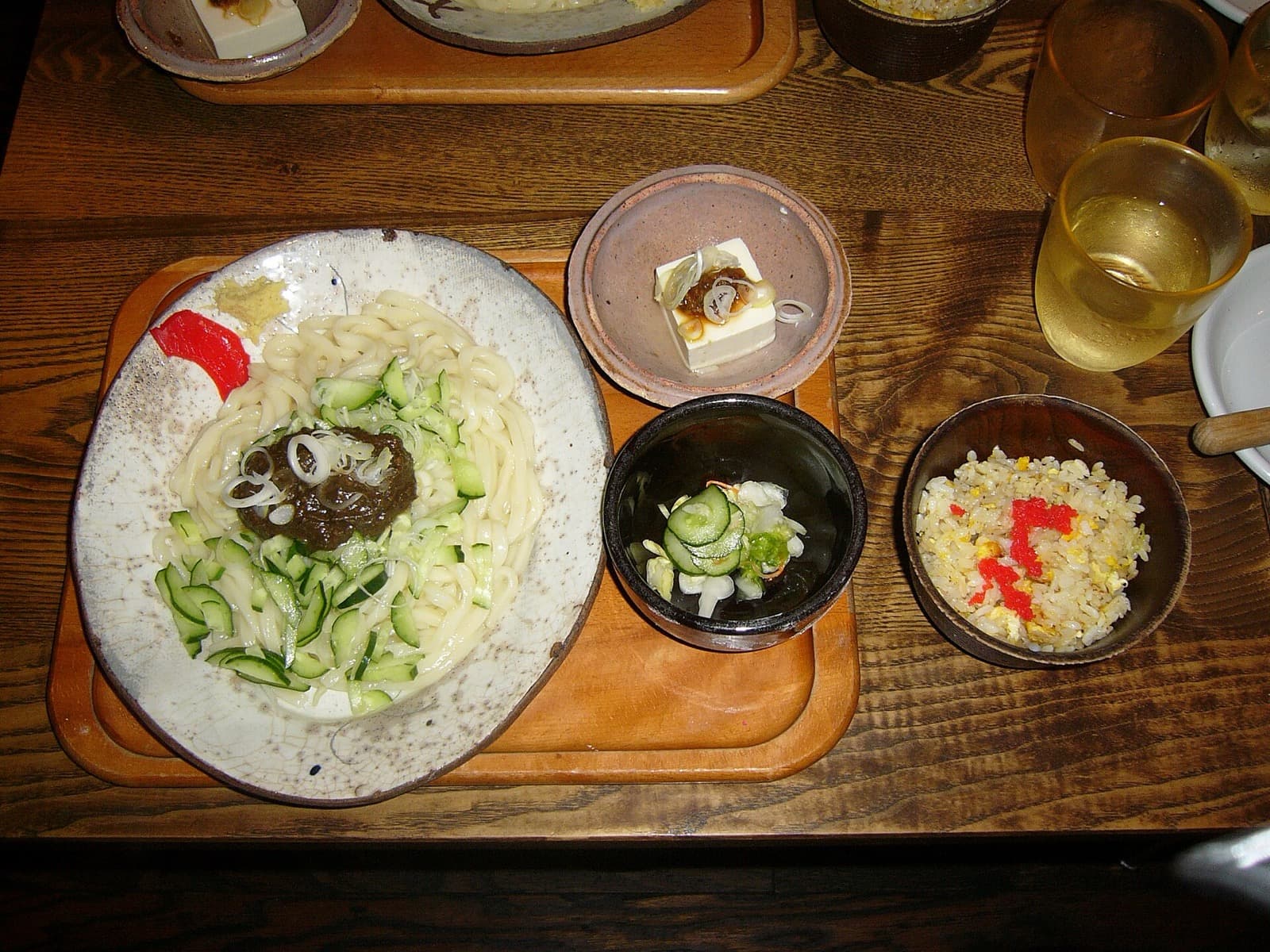 A plate of jajamen noodles topped with meat miso, cucumber and leek, with small side dishes