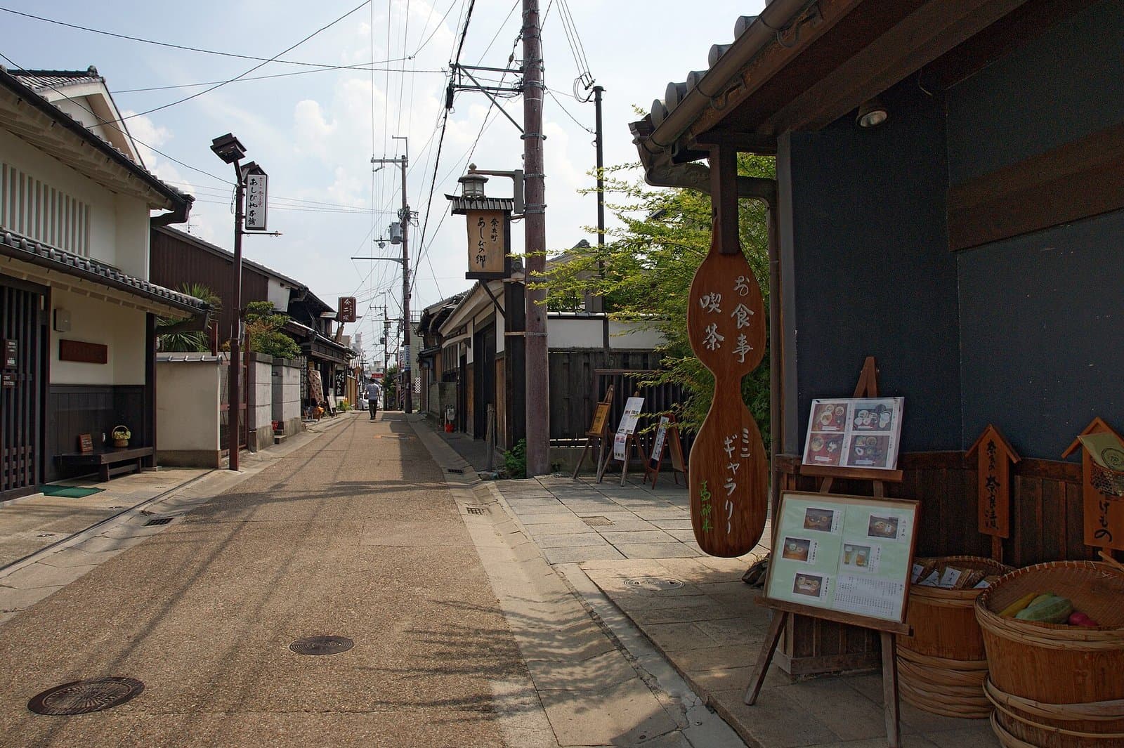 A quiet street of old townhouses with wooden signboards and a paddle-shaped shop sign