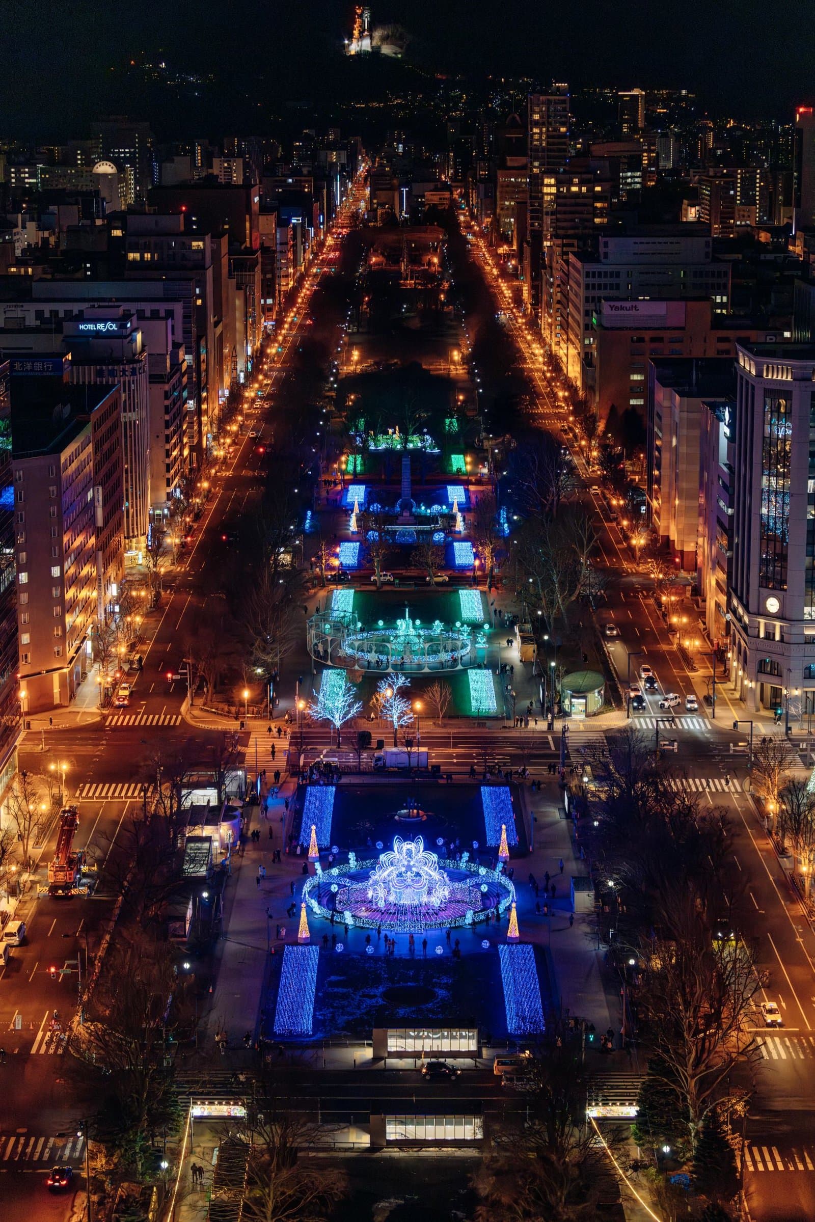 Odori Park at night from above, lit with blue and white illuminations between city streets