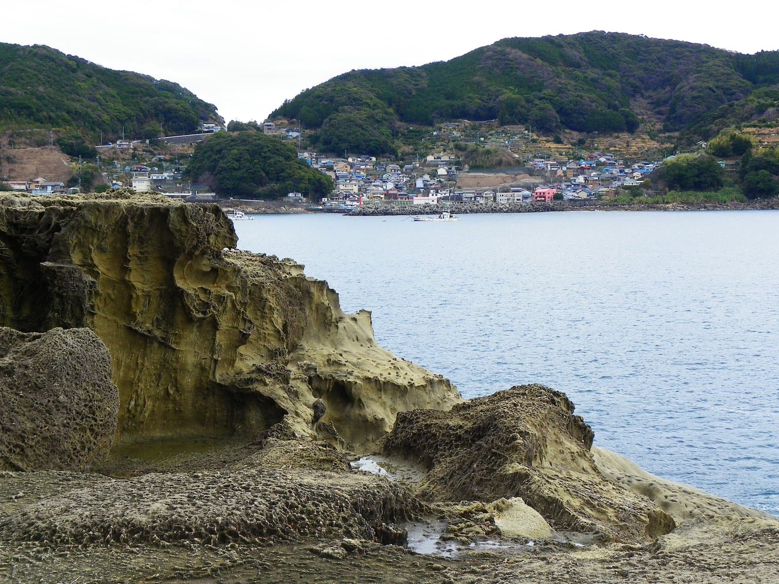 海岸の浸食された岩と、奥の湾と小さな町