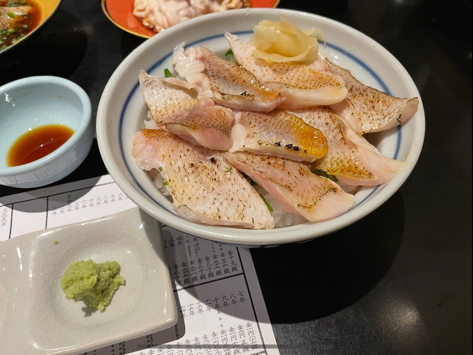 A rice bowl topped with seared blackthroat seaperch fillets and ginger, with wasabi and soy sauce