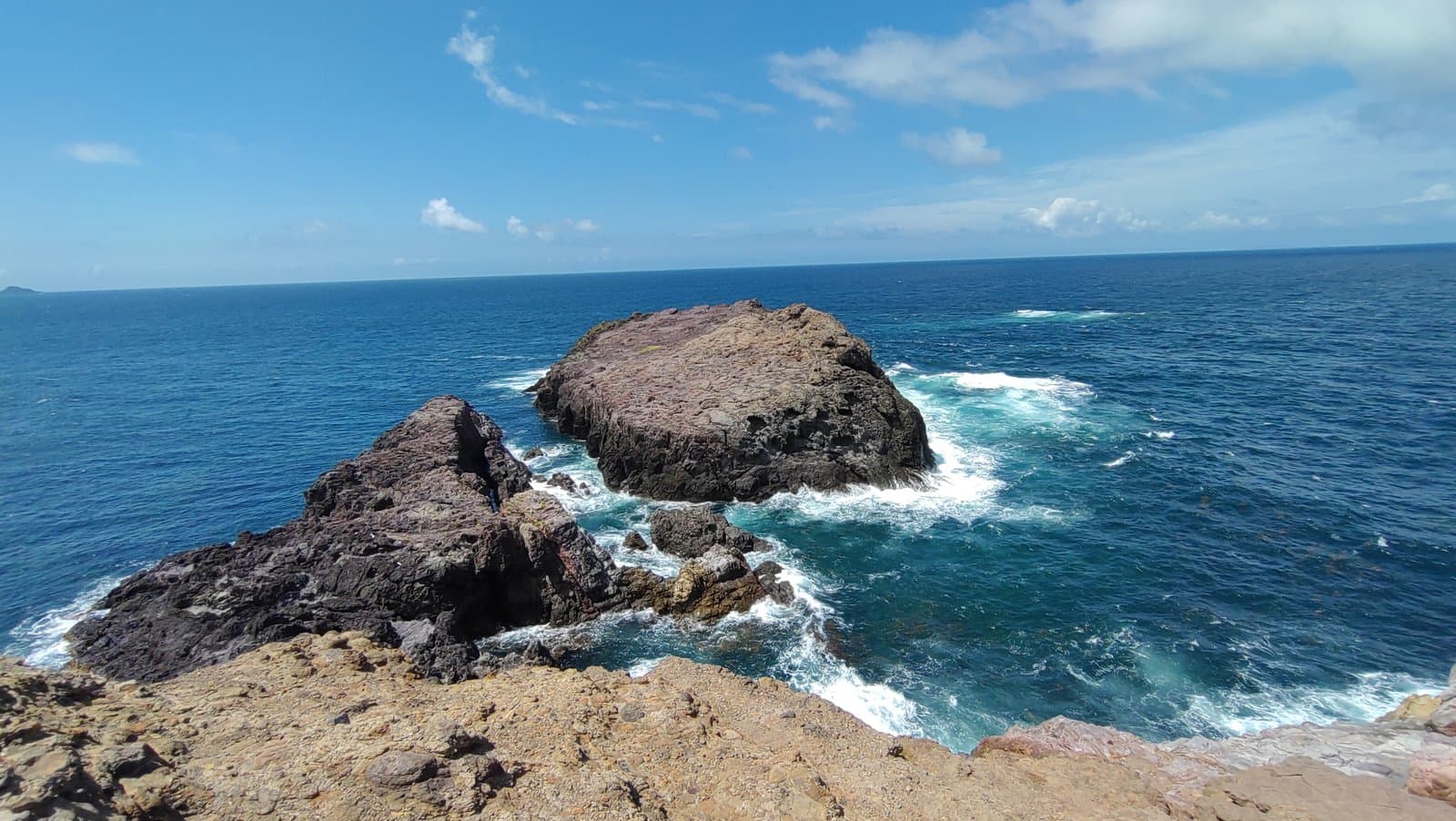 A rocky point jutting into a blue sea with white surf
