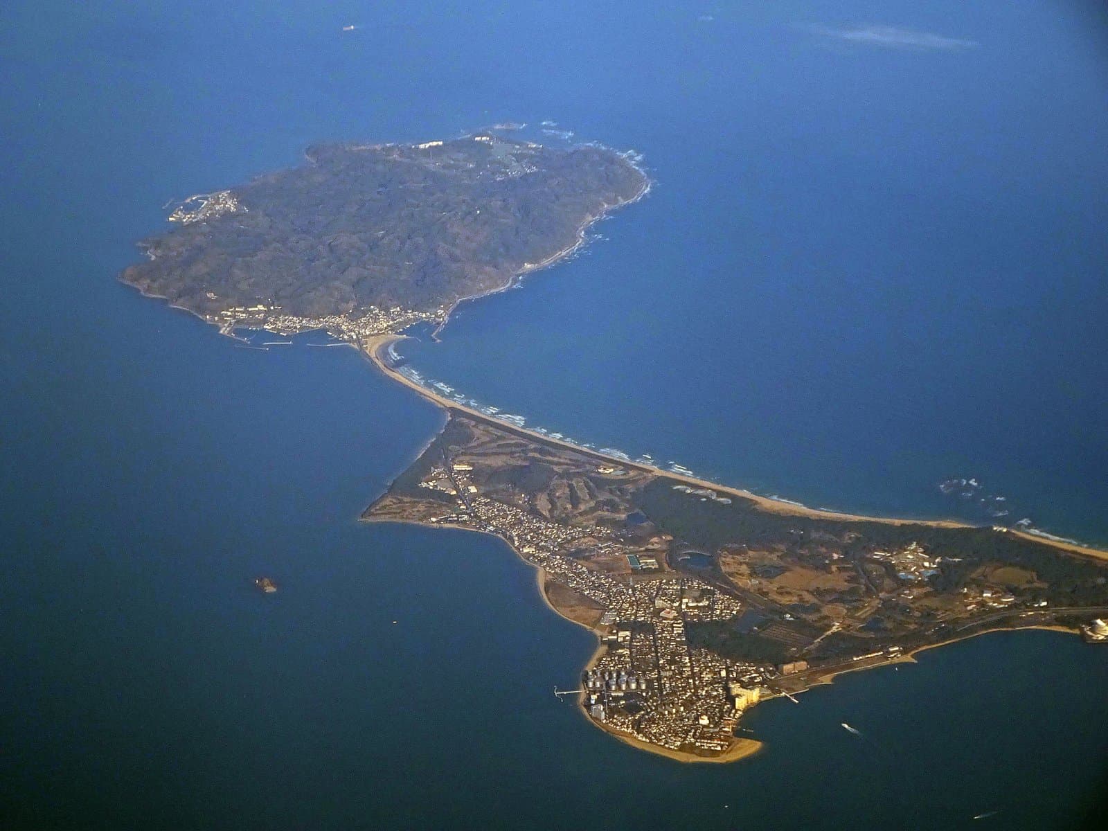 上空から見た、細長い砂州で陸とつながる島と青い海