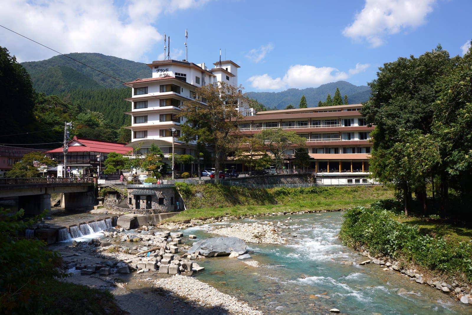 A clear blue-green river running past hot-spring inns below green mountains