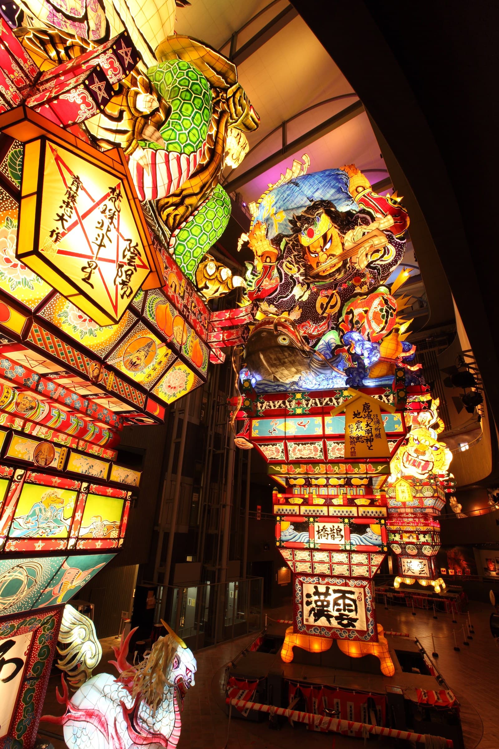 Towering lit-up Tachineputa floats inside a tall atrium