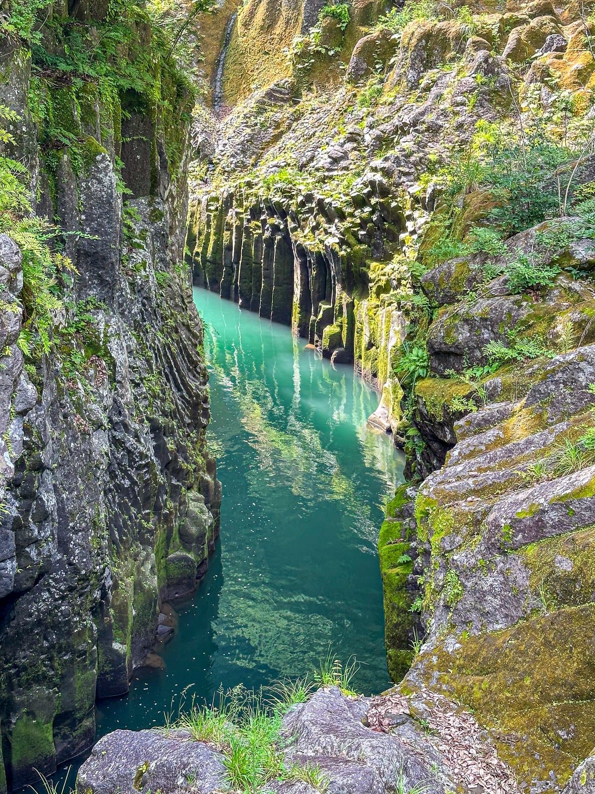 A turquoise river deep in a narrow gorge of columnar basalt cliffs