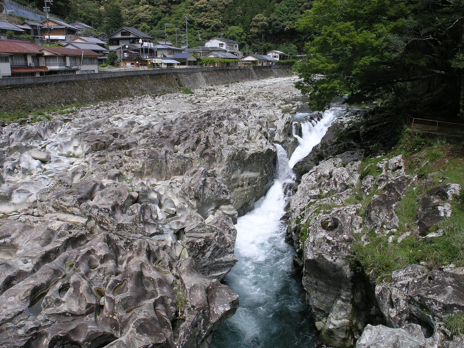くぼみの多い灰色の岩床を流れ落ちる滝