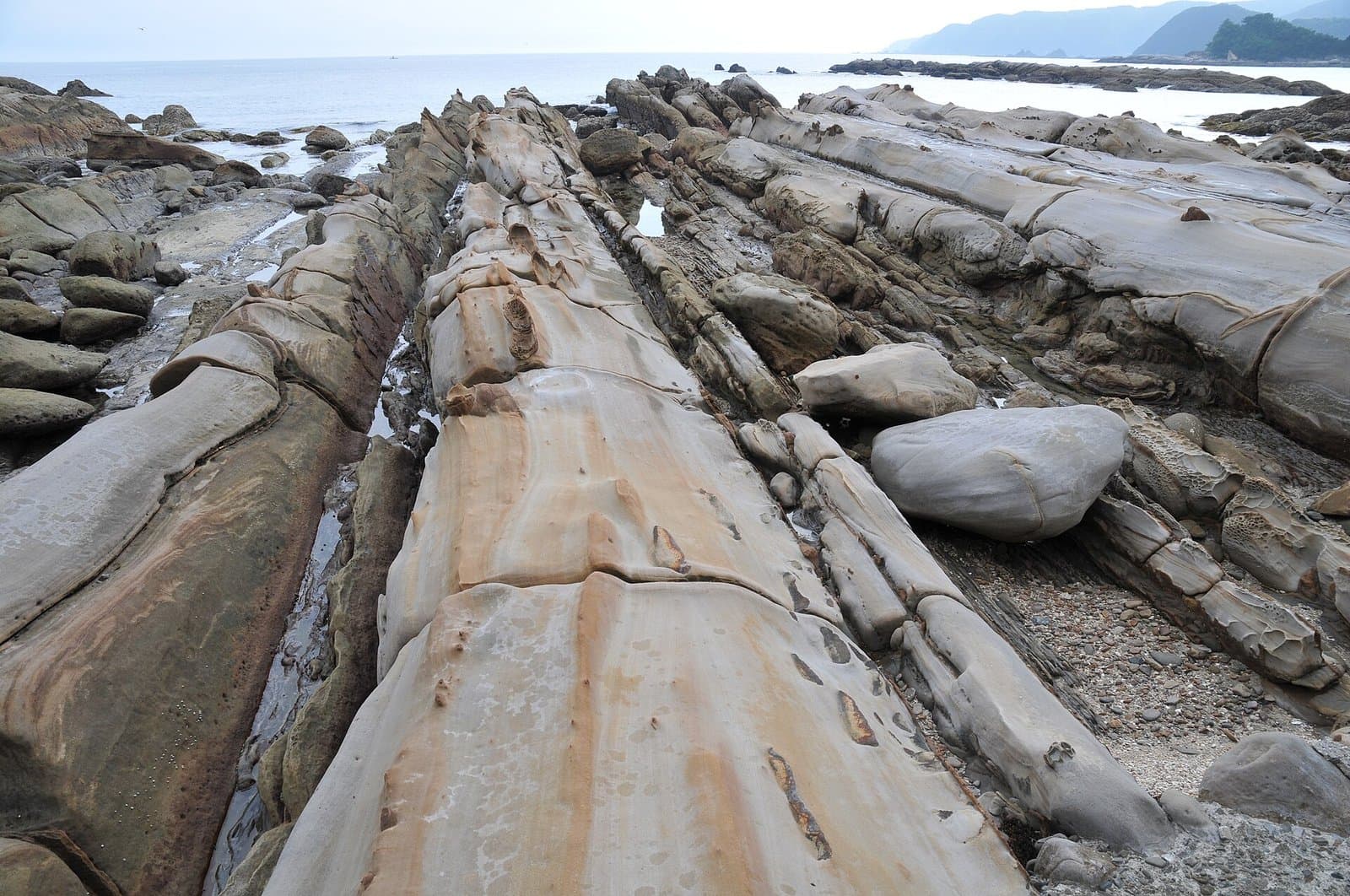 Long ridges of striped, wave-worn rock stretching toward the sea