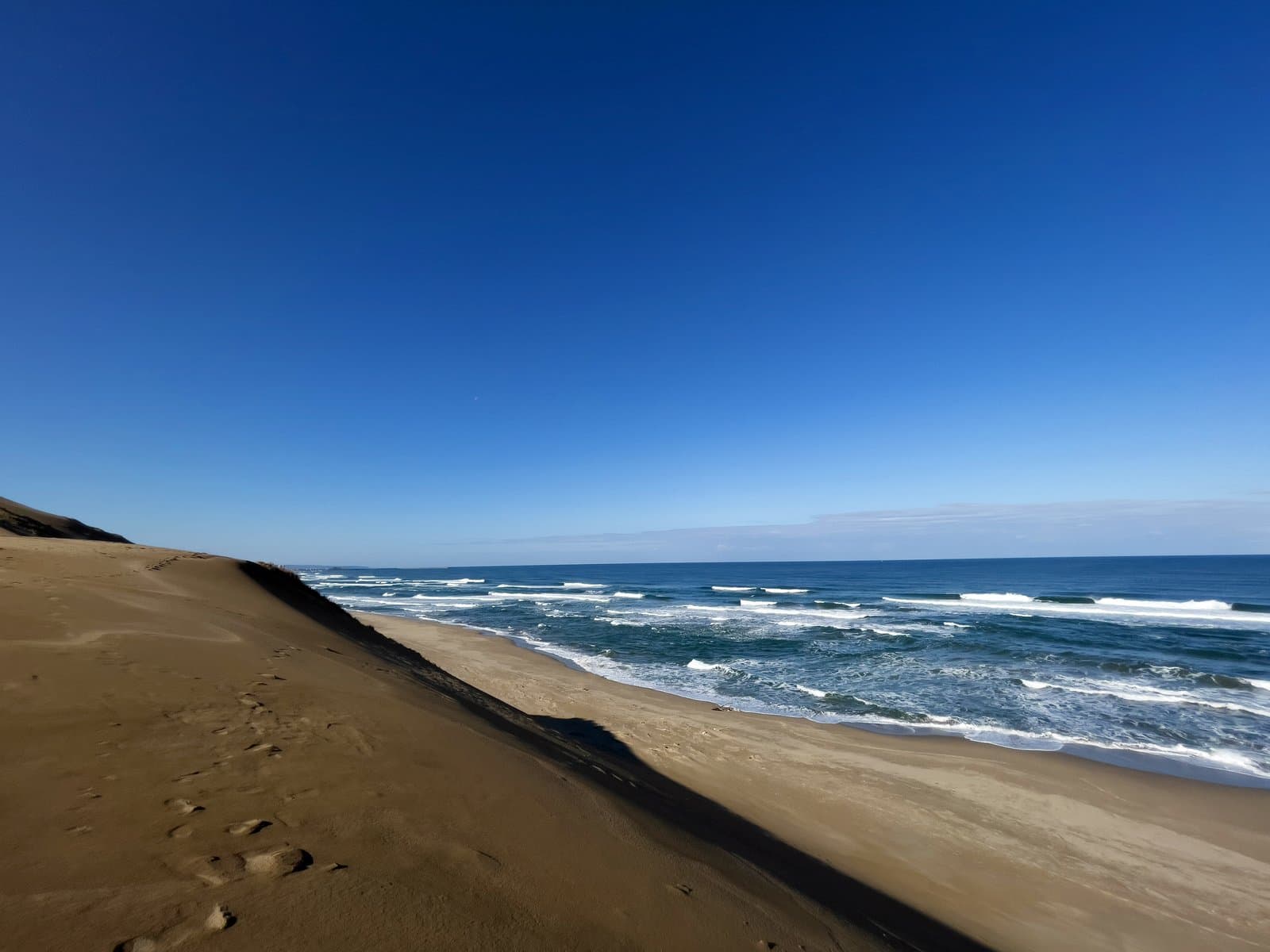 A slope of sand dunes above the waves of the Sea of Japan