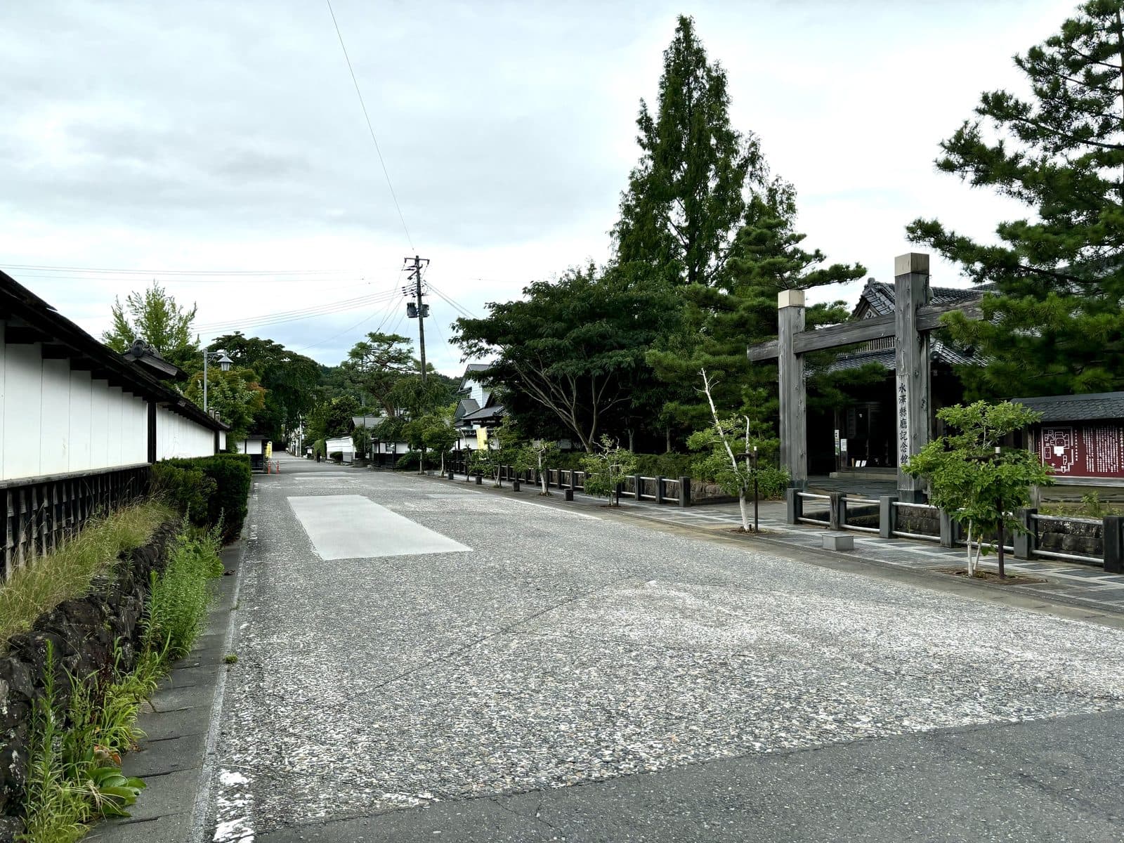 A quiet street in Toyoma with white earthen walls and pine trees