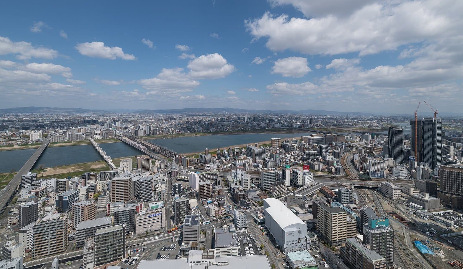 A wide view over Kita Ward and the Yodo River with its bridges under a blue sky with clouds