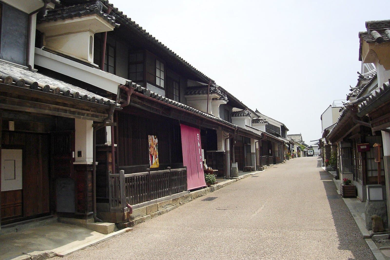 A quiet street lined with old white-walled merchant houses with tiled roofs