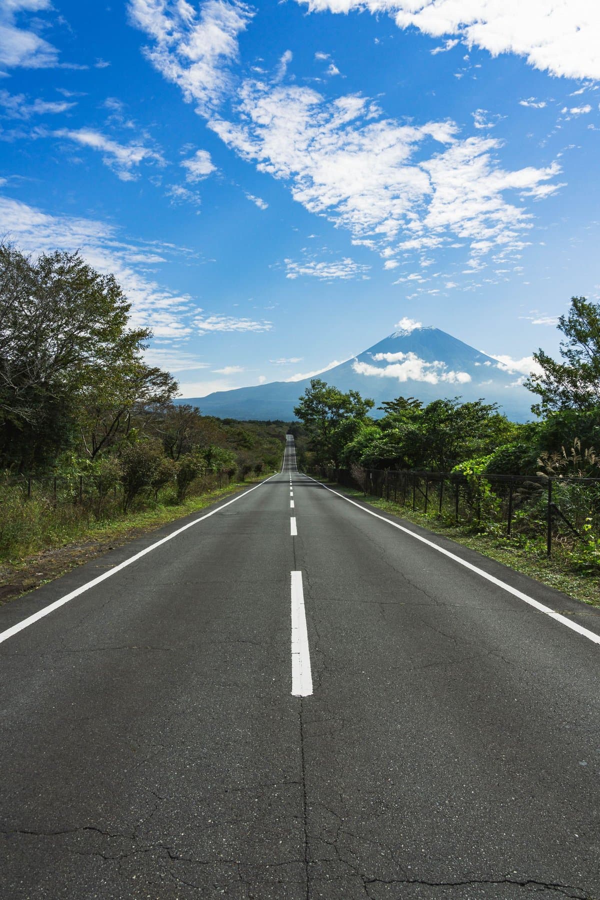 A straight road leading toward Mt. Fuji under a blue sky