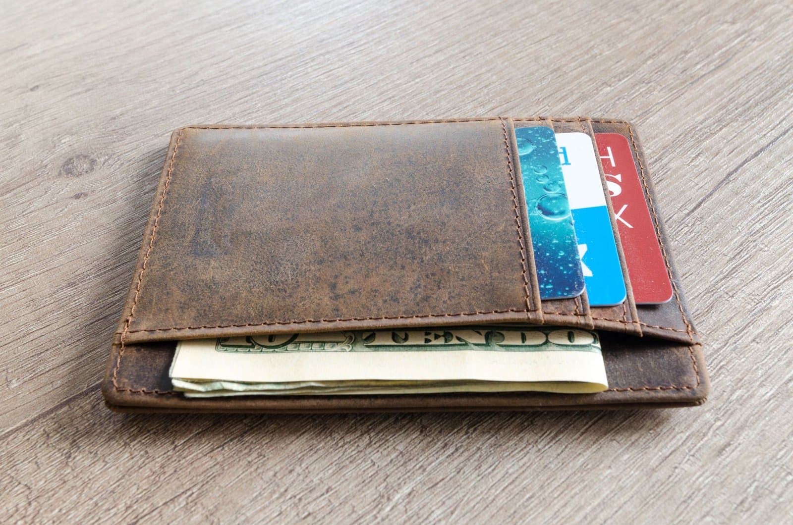 A leather wallet with cash and cards on a table