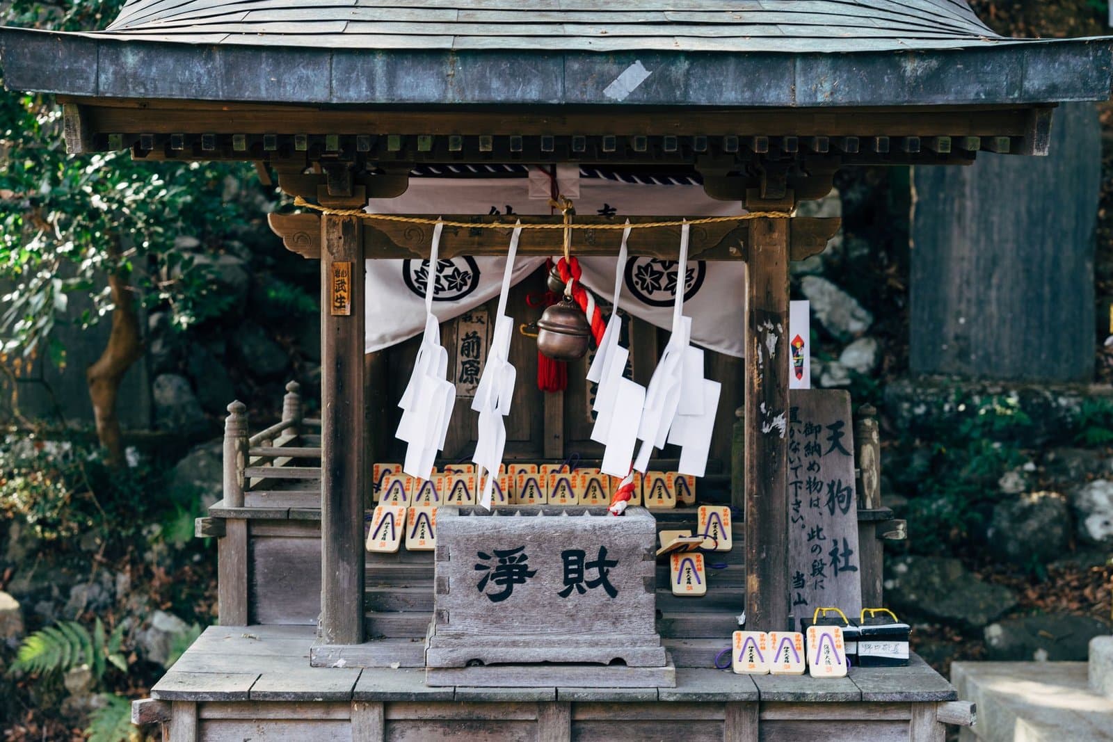 A small shrine with paper streamers and an offering box