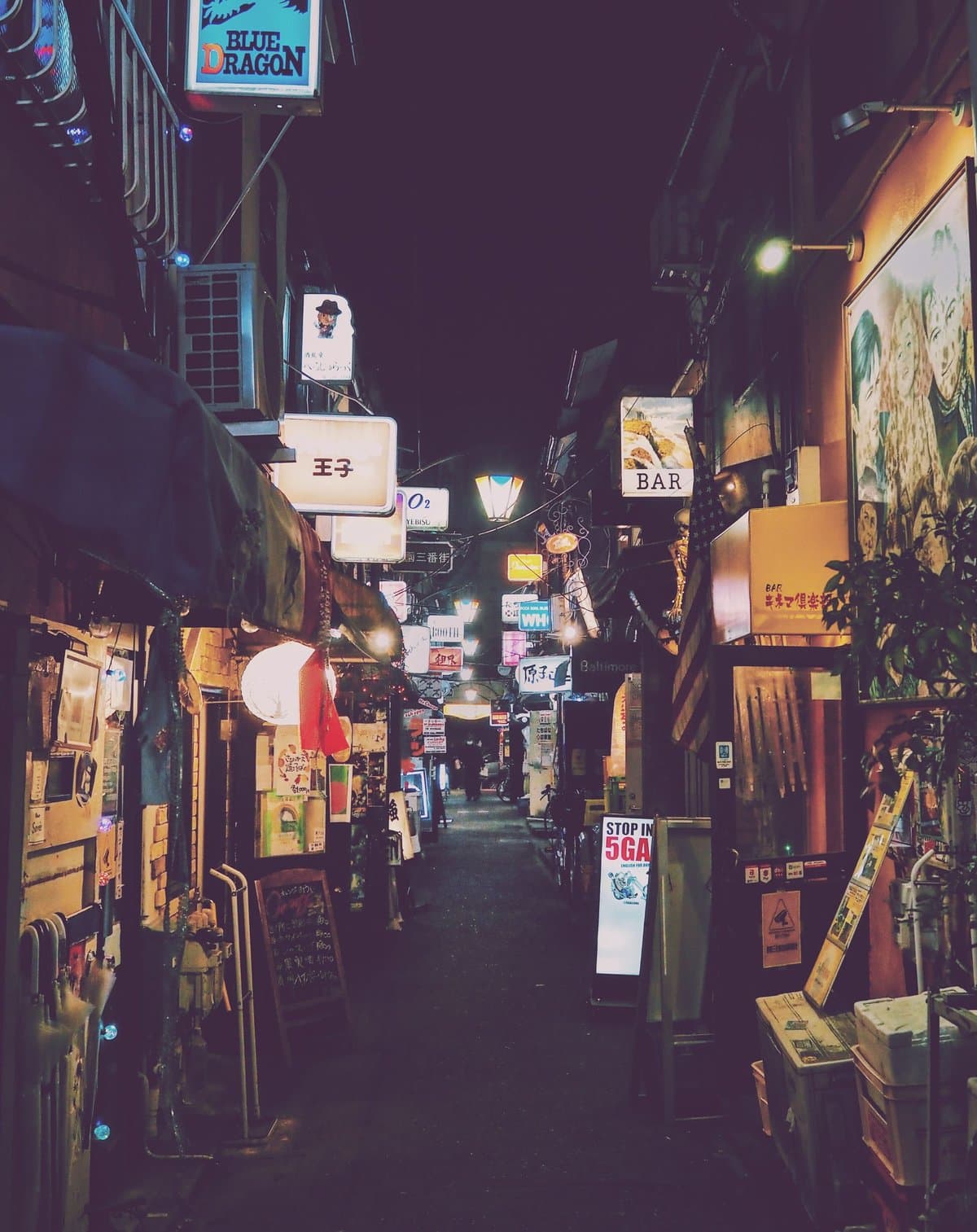 A narrow alley of small bars lit up at night