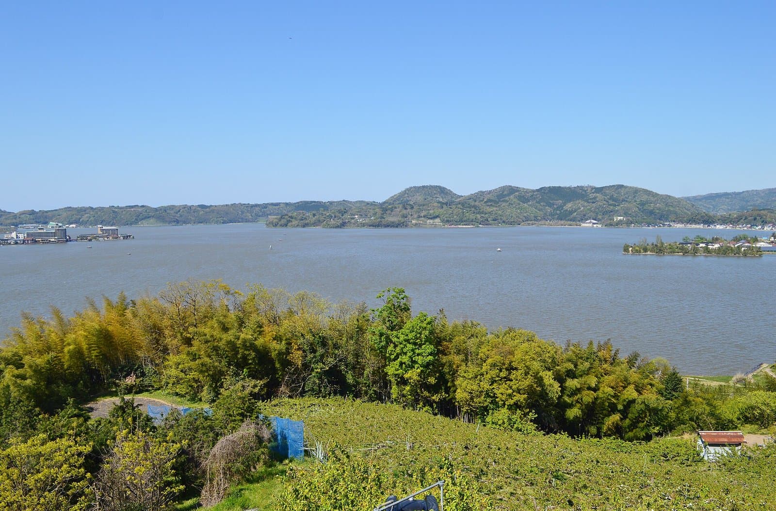 緑の丘から見た、低い山々に囲まれた広い湖