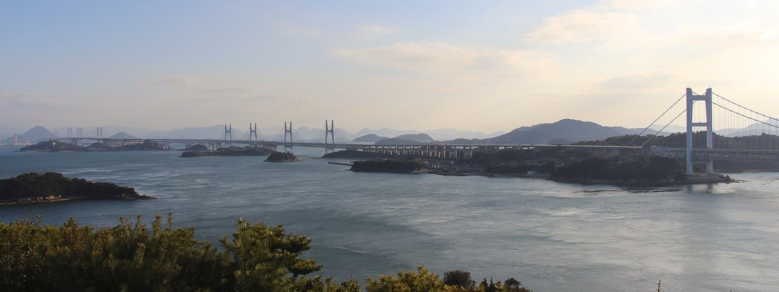 A wide view of islands and a long bridge across the Seto Inland Sea at dusk